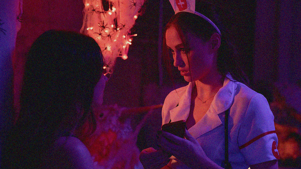 Landry Bender (left) looking at Madison Lintz during a Halloween party, the latter in a nurse costume.