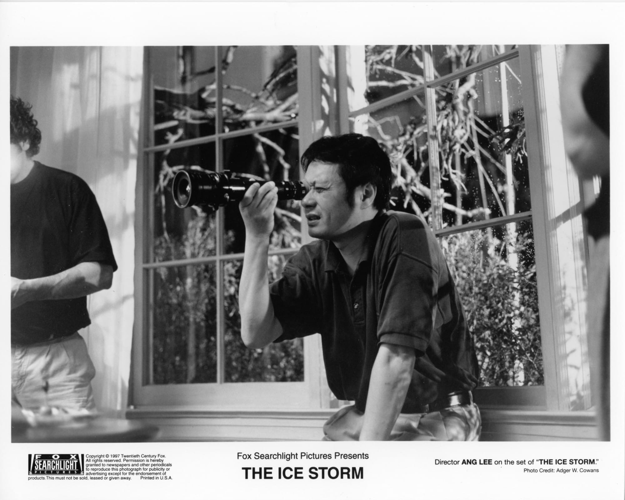 Black and White publicity photo from THE ICE STORM with Ang Lee looking through a viewfinder on set.