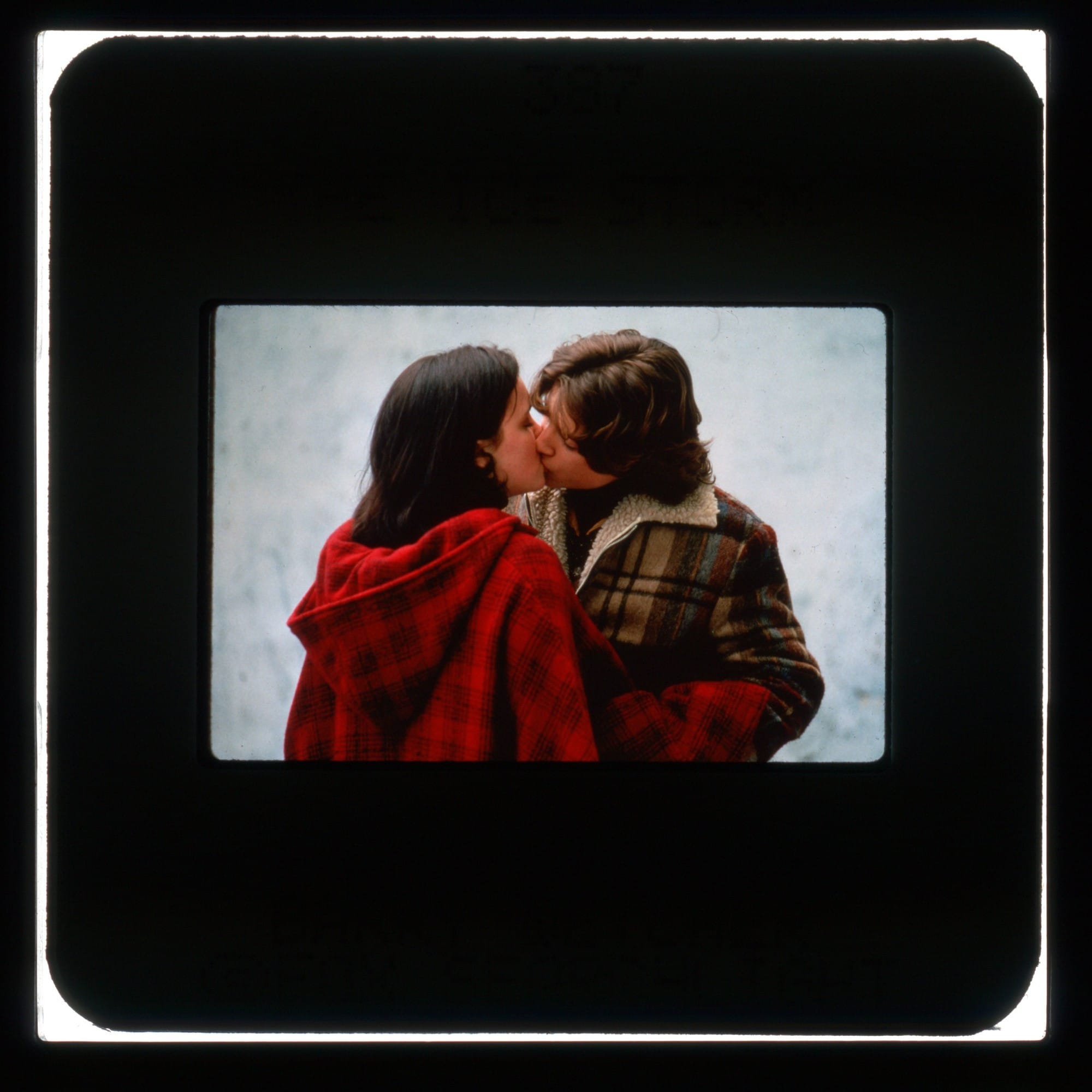 Color slide with publicity photo from THE ICE STORM featuring Ricci and Wood kissing outside in flannel coats.