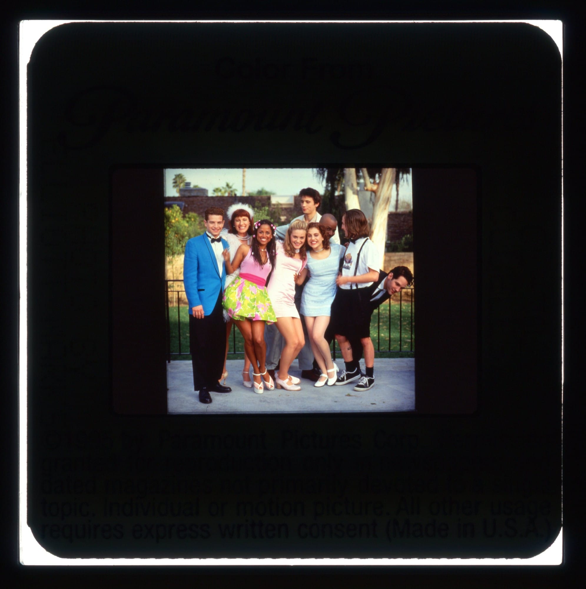 Color slide with a publicity shot of the cast from CLUELESS posing outside in front of a waist-high iron fence.