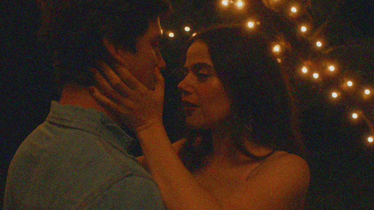 A close-up of man and woman, presumably dancing, with her hands cradling his face.