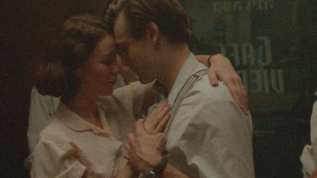 A man and woman dance with foreheads touching.