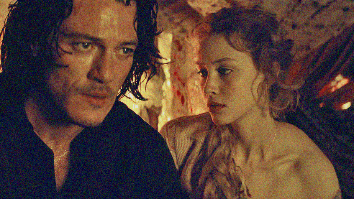 A woman looks worryingly at a very distressed man sitting next to her.