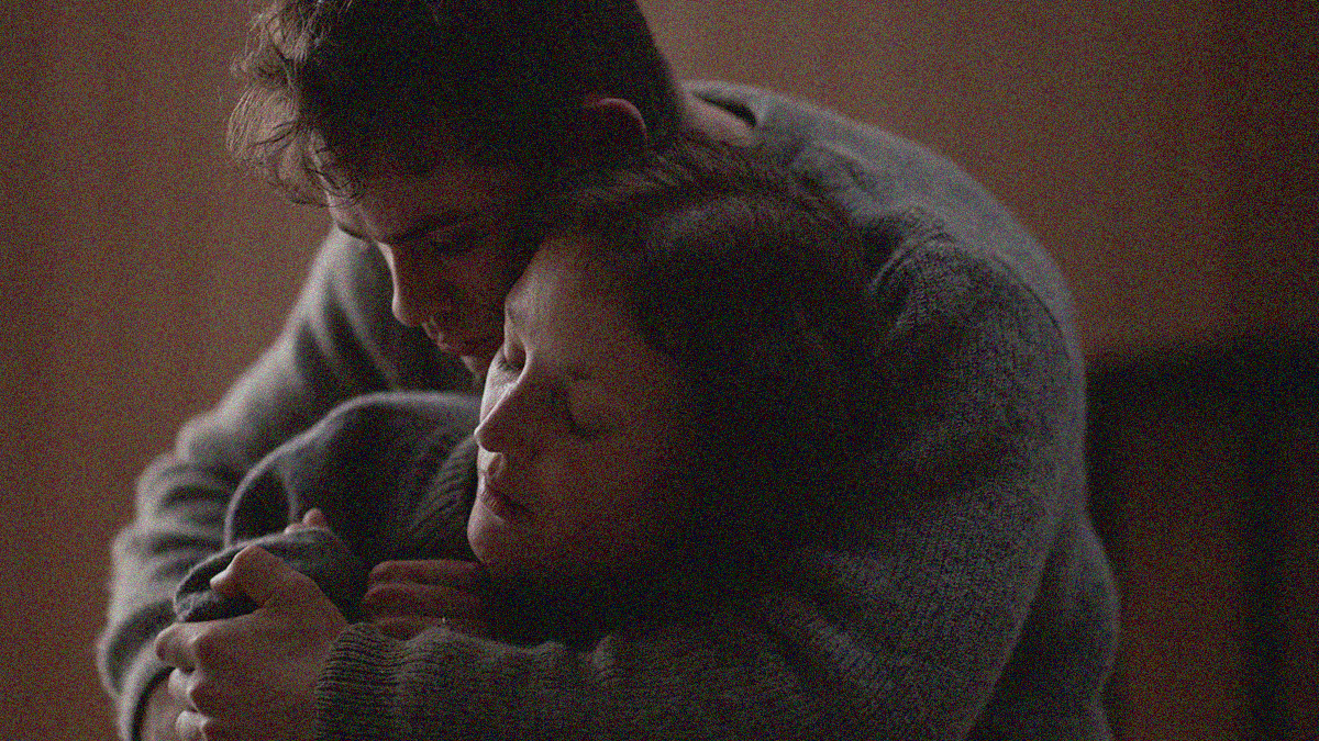 A man wraps his arms around a woman in a secure embrace.