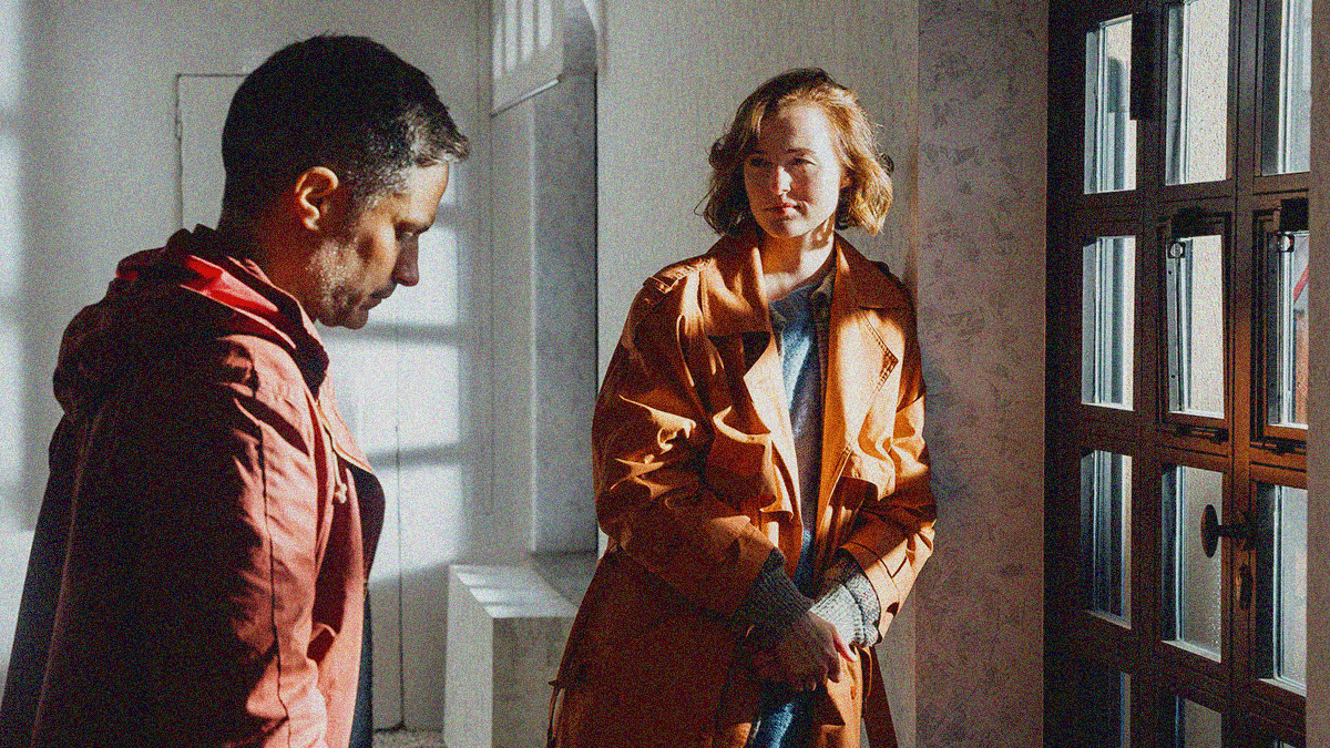 A man in profile at left facing a window at right with a woman looking at him in between.