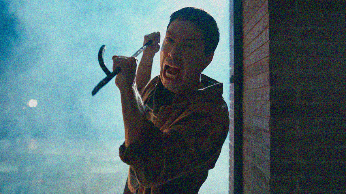 A man screams while swinging a wrought iron poker downwards in attack with both hands.