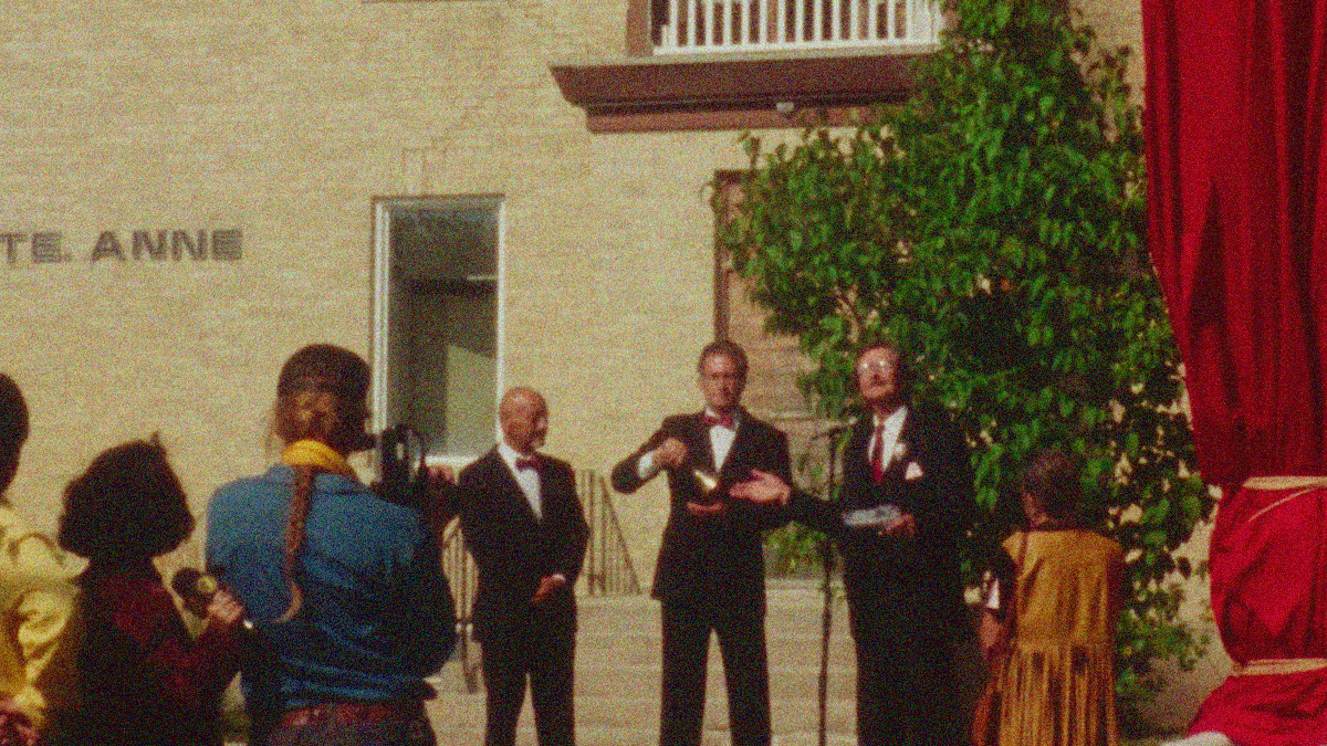 Three men in tuxedoes stand behind a microphone while a news reporter and cameraman watch.