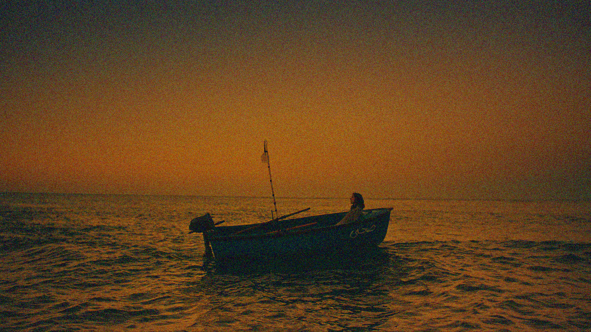 An isolated woman is leaning against the wall of a motor boat surrounded by water and sky.
