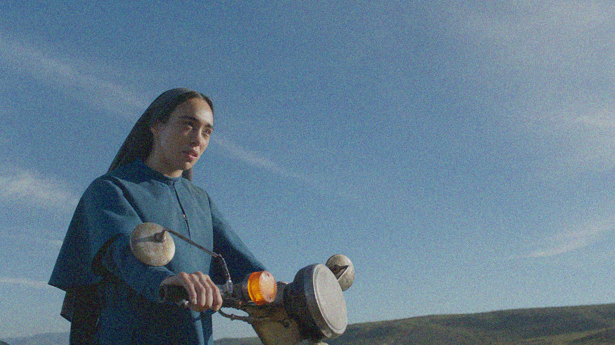 A nun riding a motorbike in the bottom left corner's third while the blue sky fills the rest of the frame.