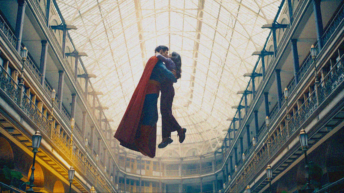 Superman and Lois Lane kissing in an embrace while floating in the air within a two-story wraparound structure with giant glass sunroof above.