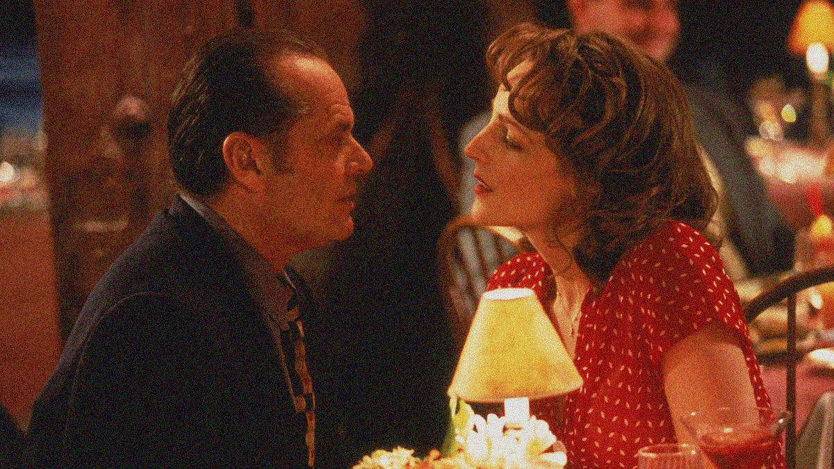 A man and woman look into each other's eyes sensually while sitting at a restaurant table.