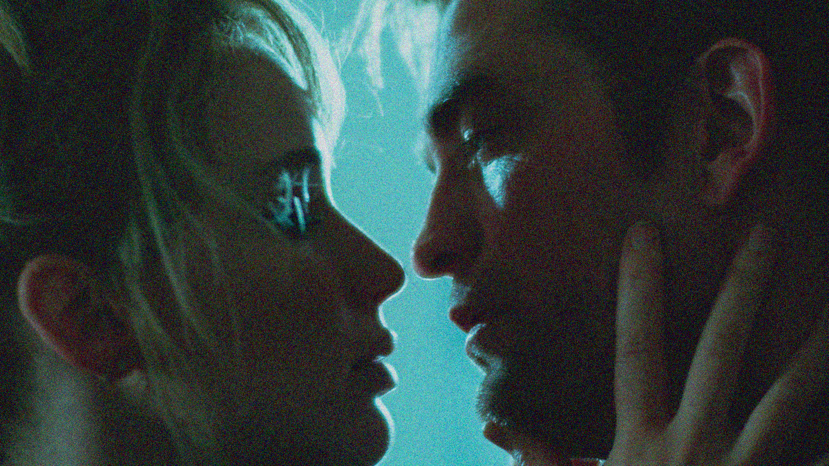 Close-up of a woman (left) and man's (right) faces coming in for a kiss. Her hand is seen on his neck.