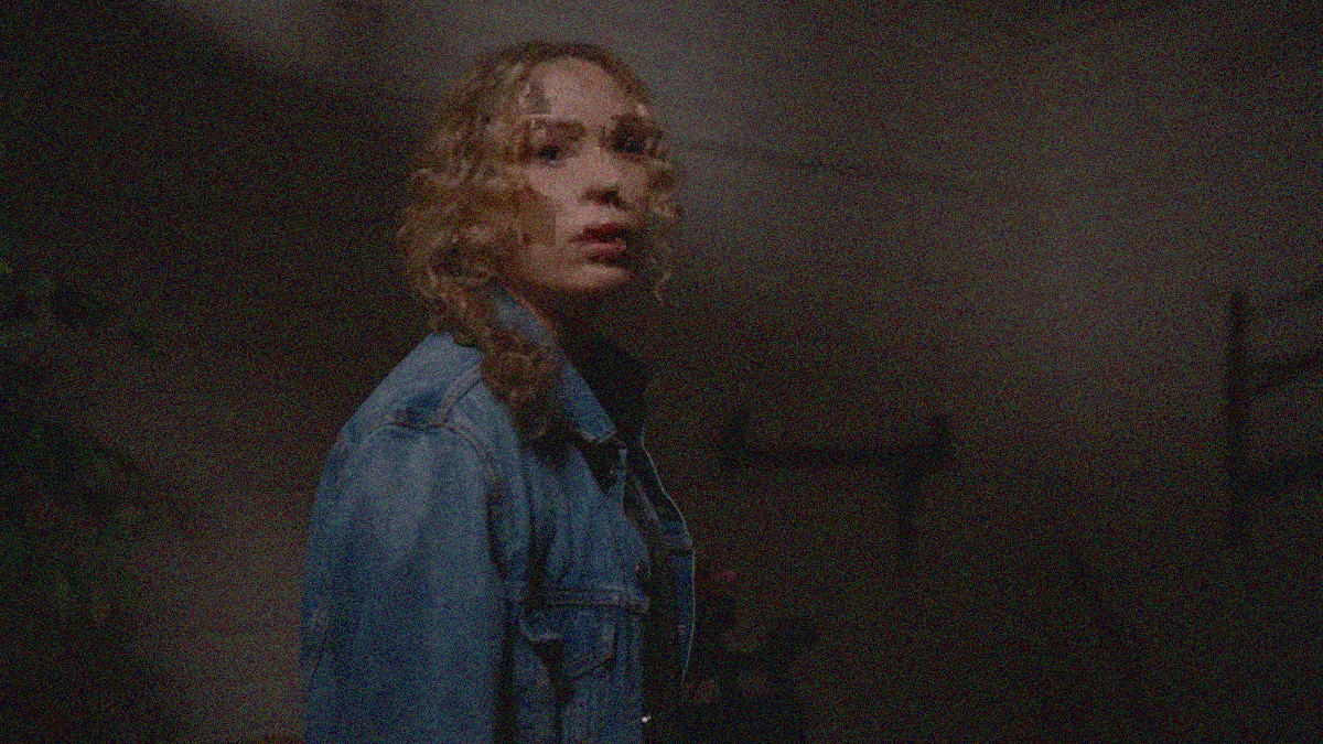 A pixelated and distorted image of a woman in jean jacket looking past the camera.