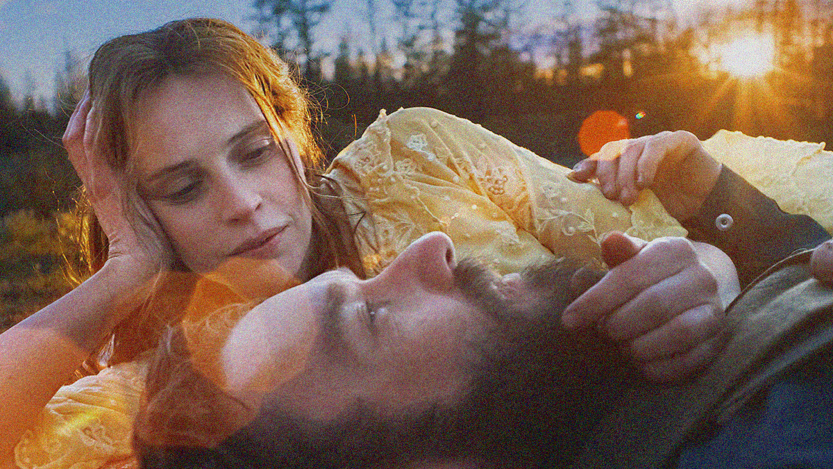 Close-up of a man on his back looking up and a woman on her side looking at him with head propped in hand.