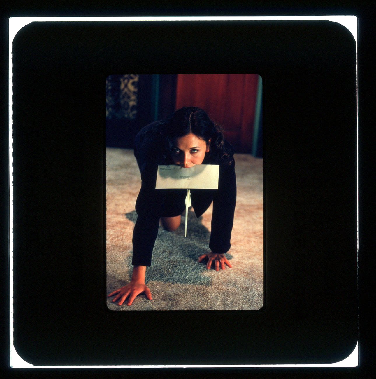 Color Publicity Slide - A woman crawls on a carpeted floor towards the camera with a sealed envelope in her mouth.