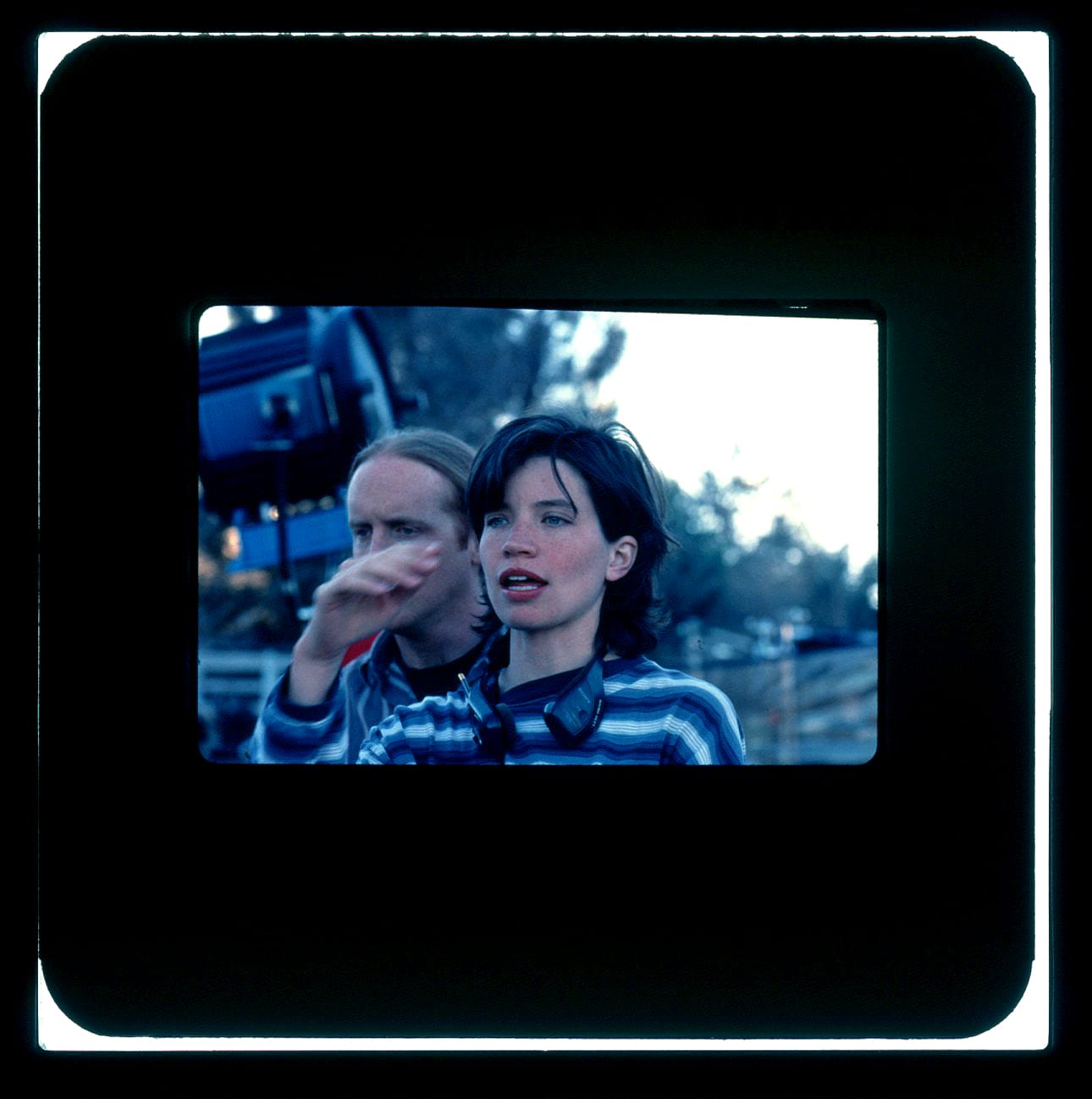 Color Publicity Slide - A woman with arm in air and giant flood light behind her speaks directions to people off-screen.