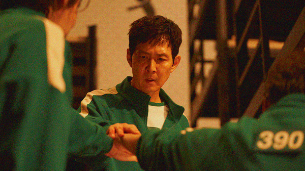 A man looks down at his outstretched hand on top of two other people's hands in a show of solidarity between them.